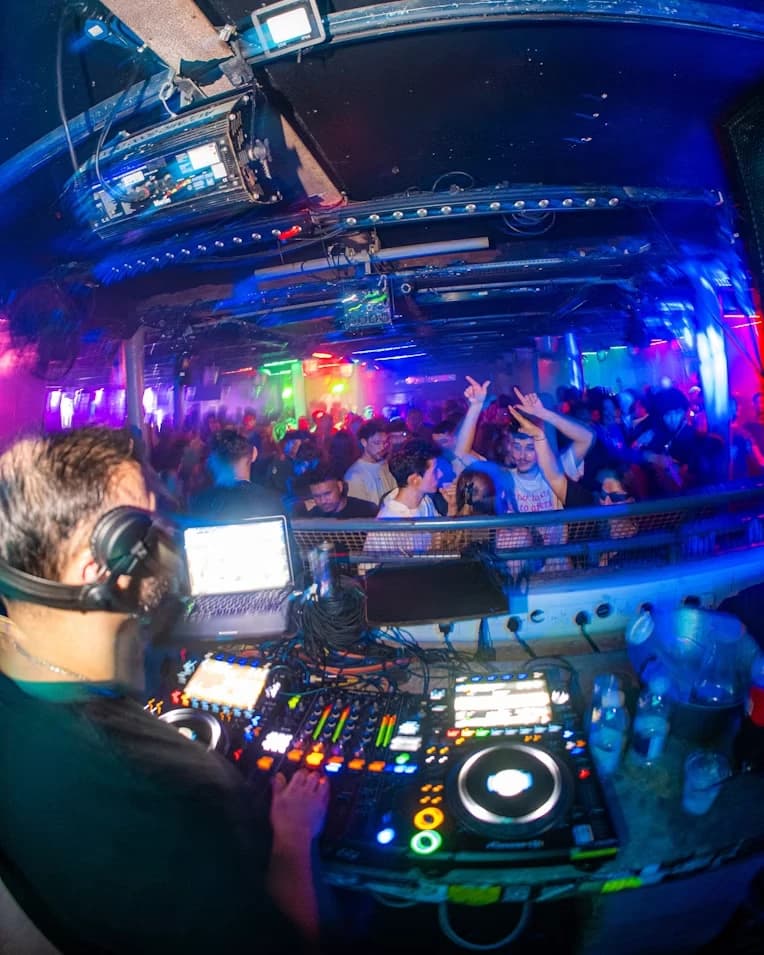 A DJ at the decks with a full floor in front of them